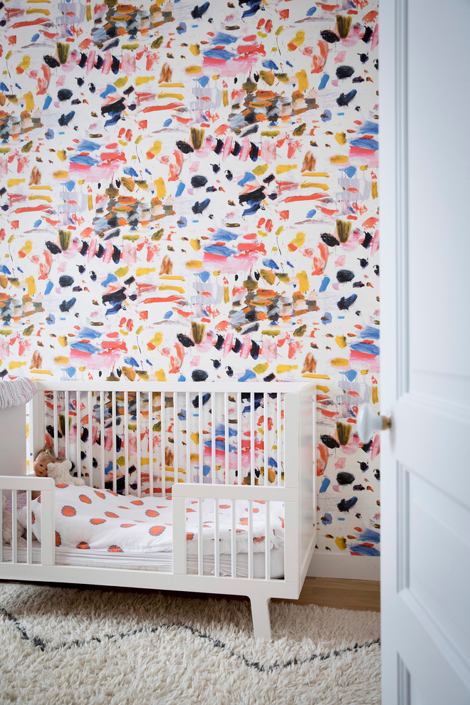 Example of a trendy light wood floor and beige floor nursery design in Paris with multicolored walls