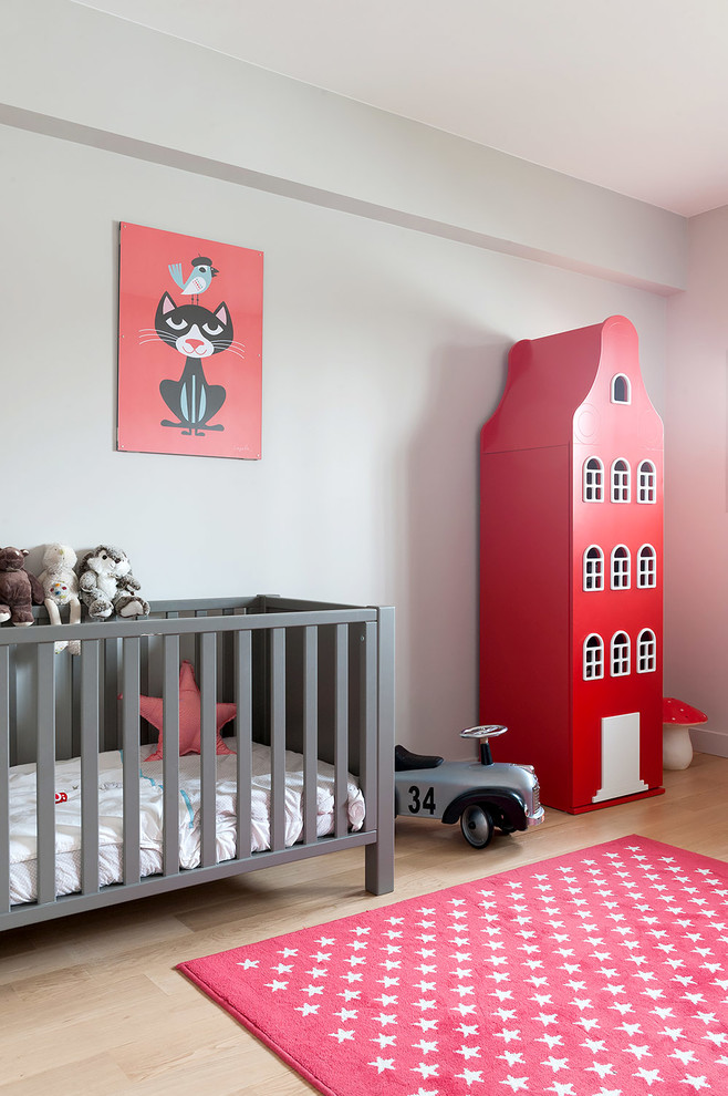 Exempel på ett mellanstort minimalistiskt könsneutralt babyrum, med grå väggar, ljust trägolv och beiget golv