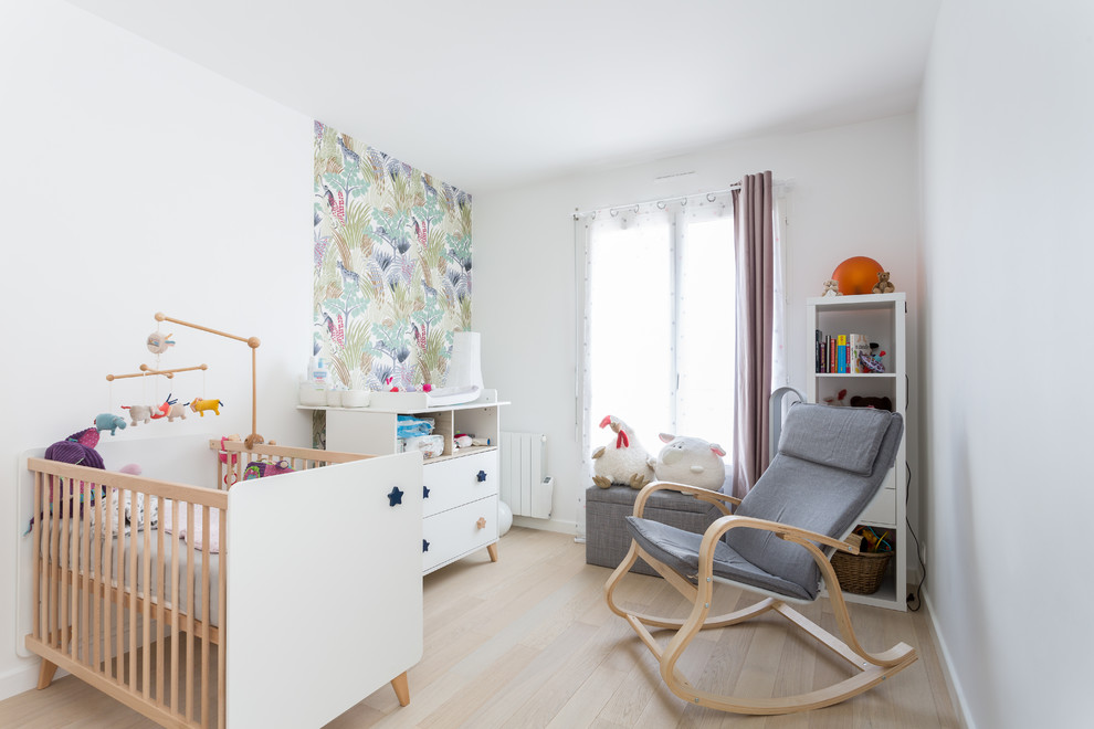 Foto de habitación de bebé neutra contemporánea de tamaño medio con paredes blancas, suelo de madera clara y suelo beige