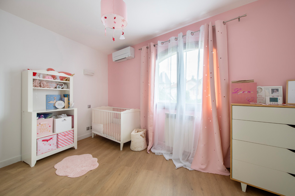 Inredning av ett modernt mellanstort babyrum, med rosa väggar, laminatgolv och beiget golv