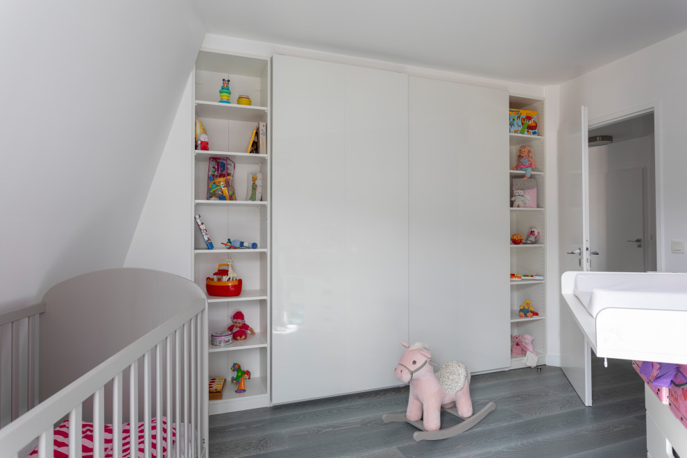 Réalisation d'une petite chambre de bébé fille design avec un mur rose, parquet clair et un sol gris.