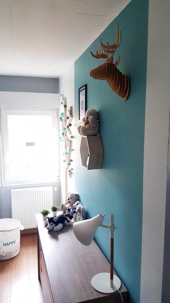 Idée de décoration pour une petite chambre de bébé garçon nordique avec un mur gris et un sol en bois brun.