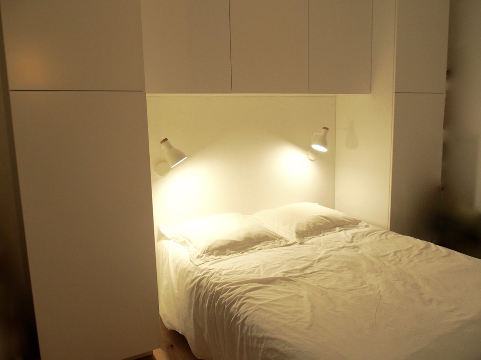 Esempio di una piccola camera matrimoniale design con pareti bianche e parquet chiaro