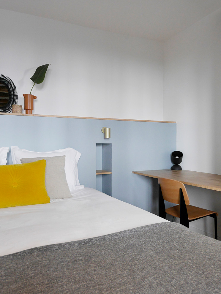 Modelo de dormitorio principal minimalista de tamaño medio con paredes azules, suelo de madera clara, suelo beige y vigas vistas