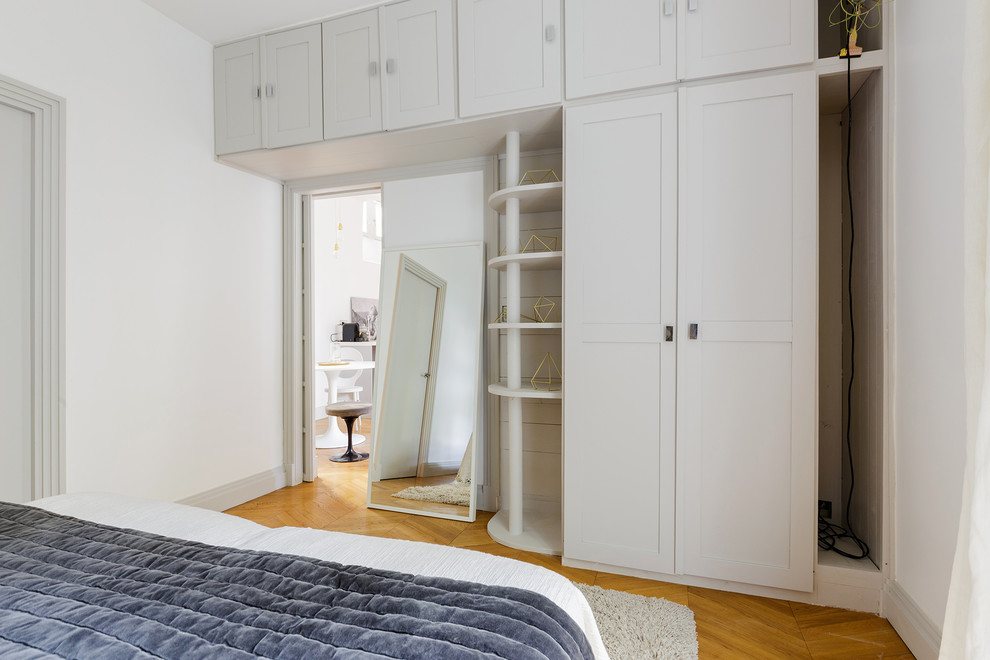 Foto de dormitorio principal actual de tamaño medio sin chimenea con paredes blancas y suelo de madera clara