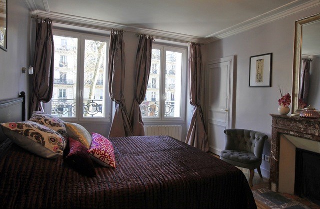Imagen de dormitorio principal clásico renovado de tamaño medio con paredes grises, suelo de madera clara y todas las chimeneas
