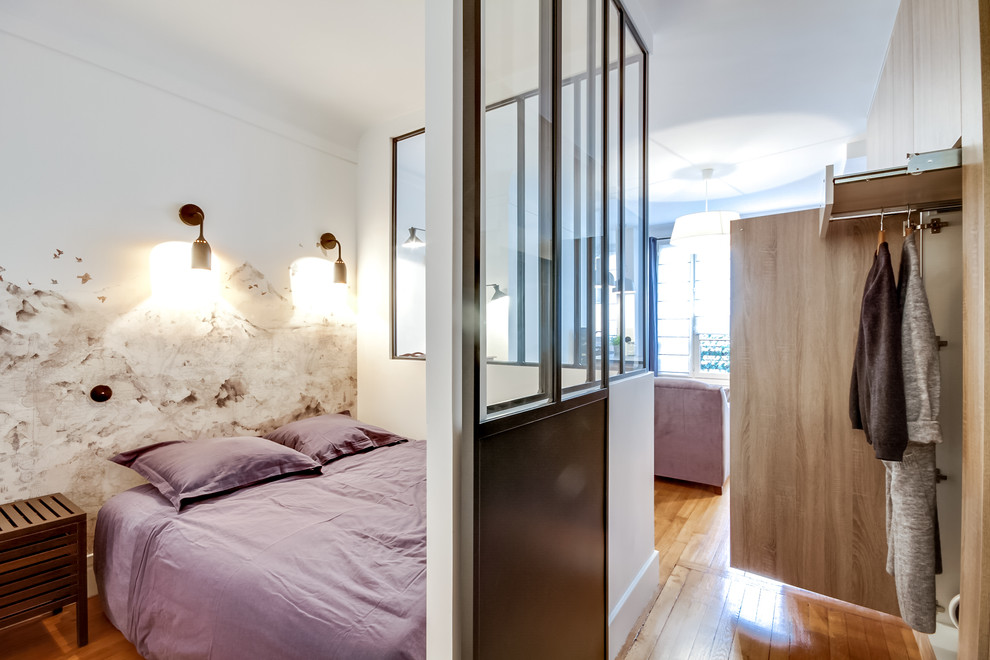 Small urban bedroom in Paris with light hardwood flooring.
