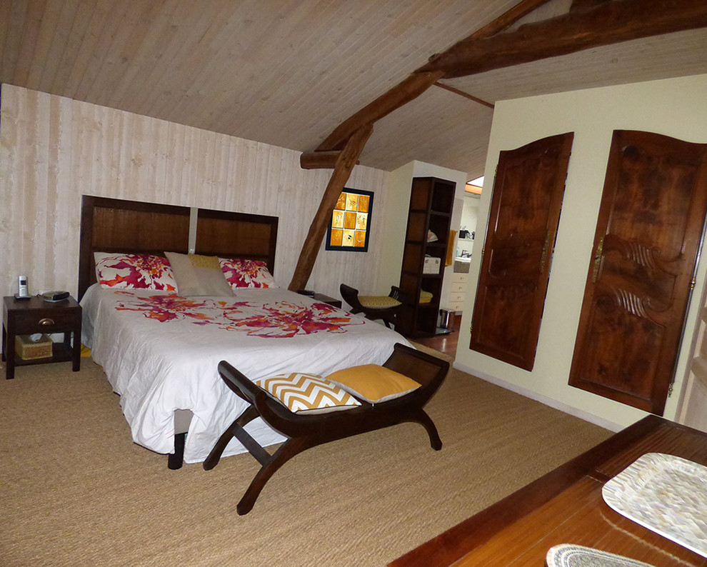 Modelo de dormitorio principal tropical de tamaño medio sin chimenea con paredes beige, suelo de bambú y suelo beige