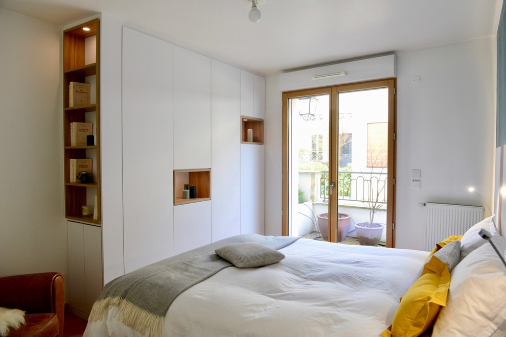 Diseño de dormitorio principal actual pequeño con paredes blancas y suelo marrón