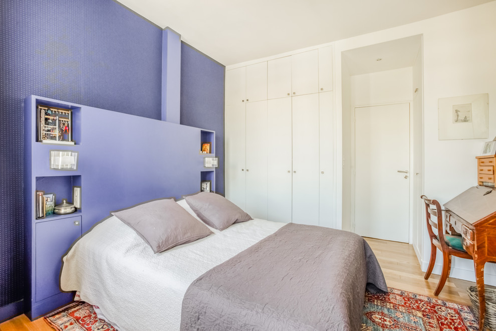 Immagine di una camera da letto minimal con pareti viola, parquet chiaro, nessun camino e carta da parati