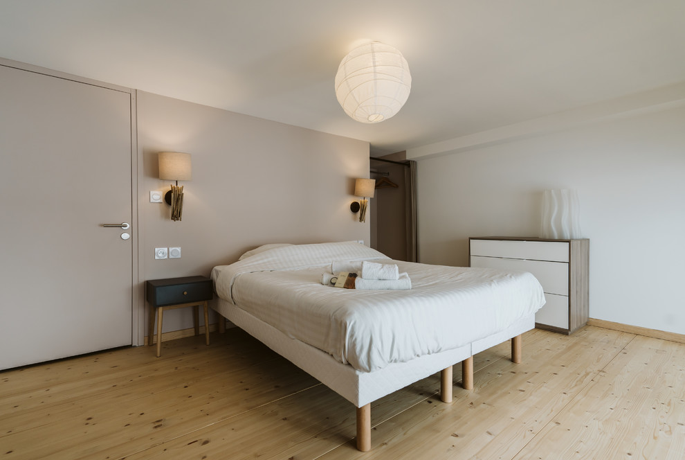 Foto de dormitorio principal contemporáneo pequeño sin chimenea con paredes blancas, suelo de madera clara y suelo marrón