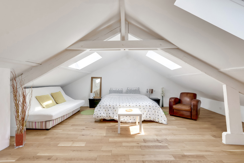 Photo of a large scandi bedroom in Paris with white walls, light hardwood flooring and beige floors.