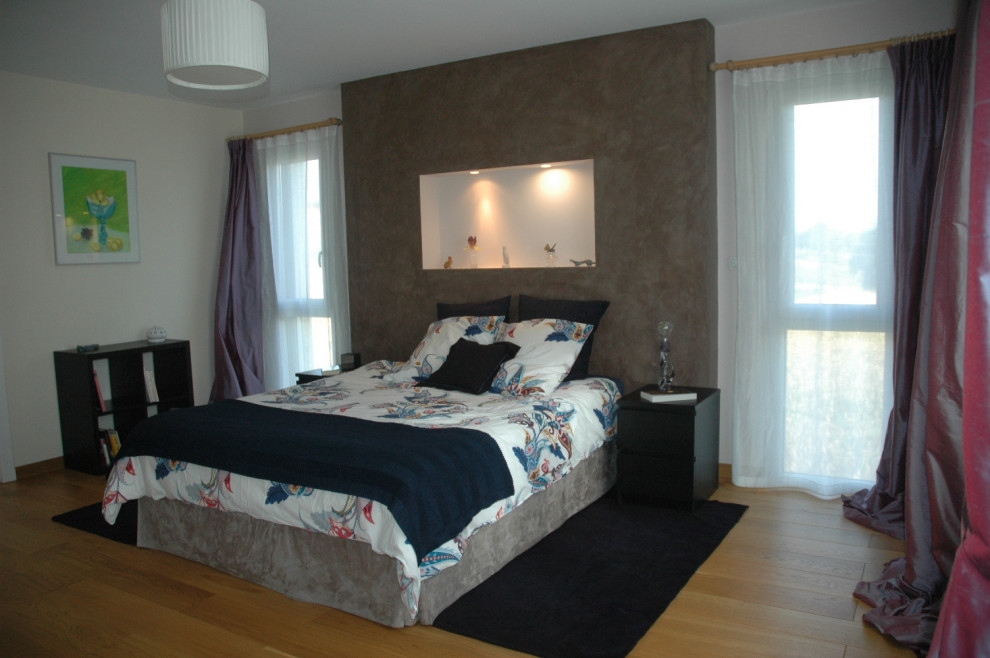 Imagen de dormitorio principal actual grande sin chimenea con paredes beige y suelo de madera clara