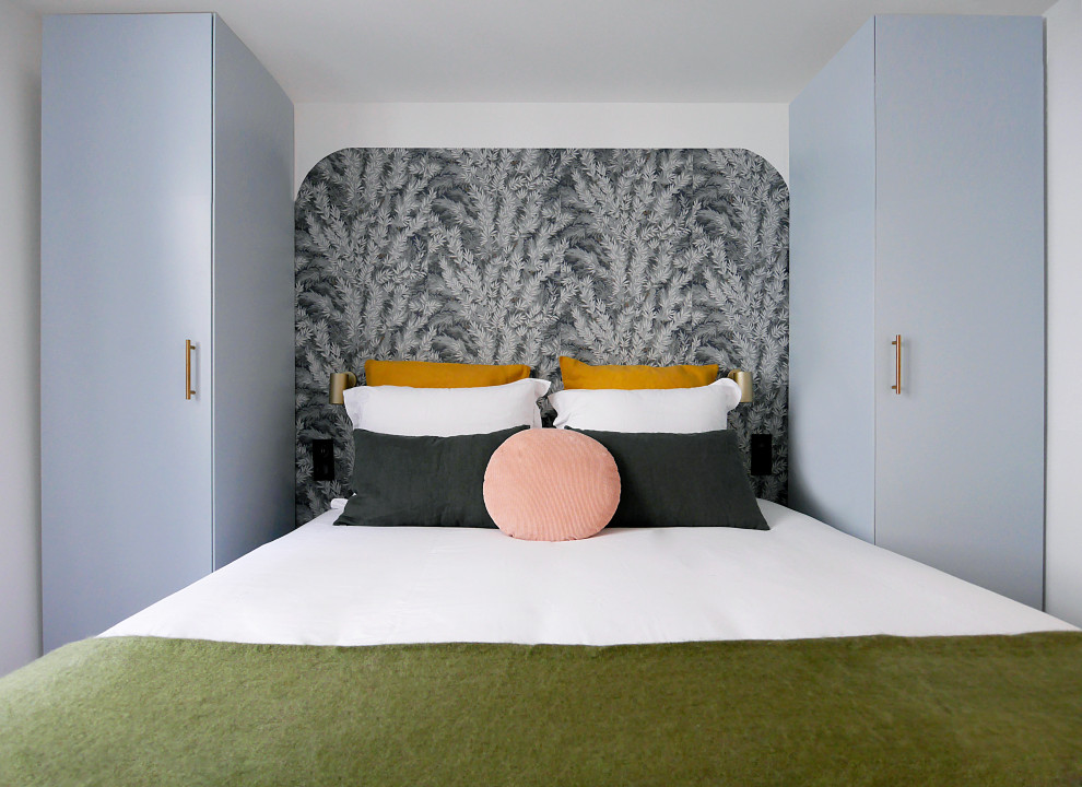 Imagen de dormitorio principal moderno de tamaño medio sin chimenea con paredes blancas, suelo de madera clara, suelo beige y papel pintado