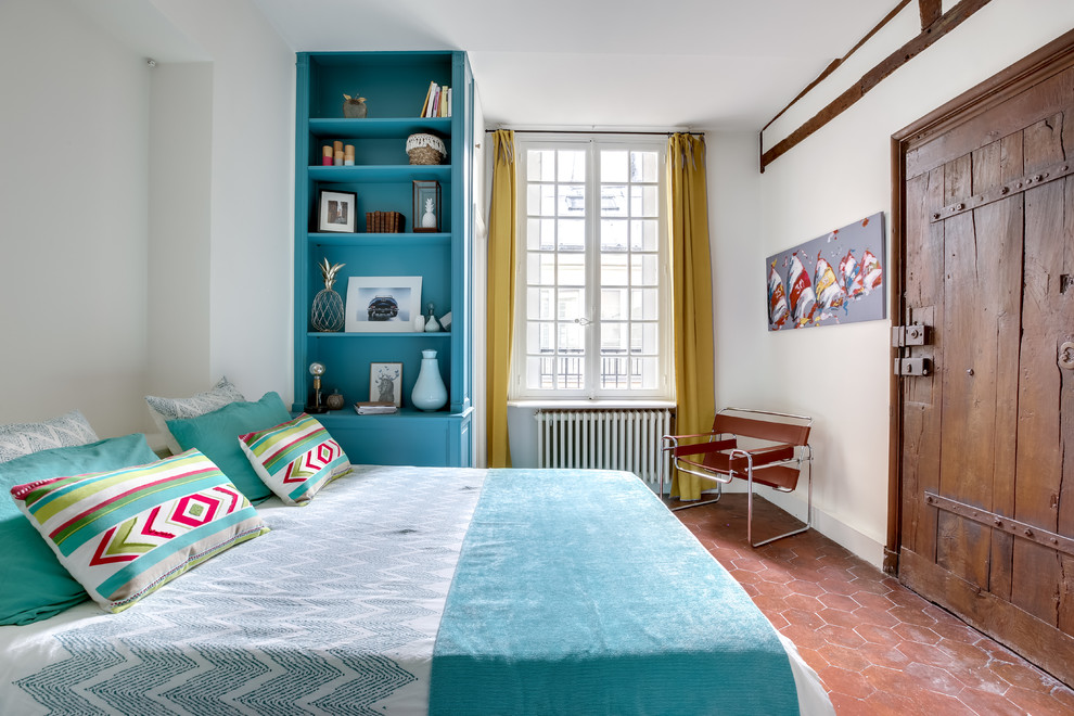 На фото: хозяйская спальня в средиземноморском стиле с белыми стенами и полом из терракотовой плитки без камина