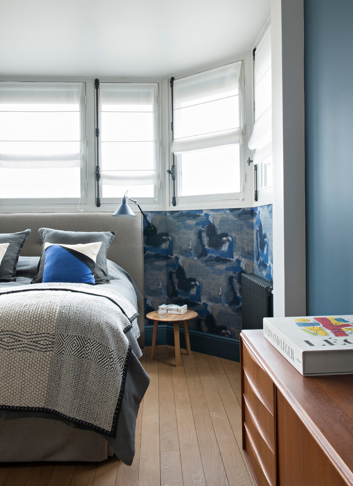 Réalisation d'une chambre design avec un mur bleu, un sol en bois brun et un sol marron.