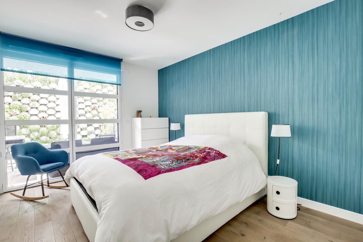 Cette image montre une petite chambre parentale minimaliste avec un mur bleu, parquet foncé, aucune cheminée et un sol marron.