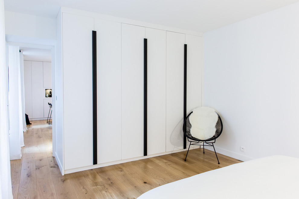 Foto de dormitorio principal contemporáneo de tamaño medio con paredes blancas y suelo de madera clara