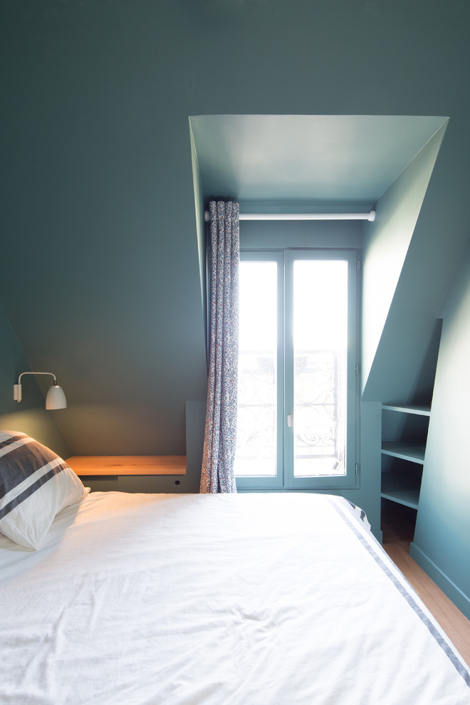Cette photo montre une chambre parentale scandinave de taille moyenne avec un mur bleu, parquet clair, aucune cheminée et un sol marron.