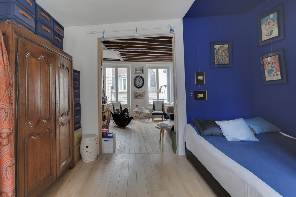 Inspiration pour une grande chambre d'amis design avec un mur bleu, parquet clair, aucune cheminée et un sol beige.
