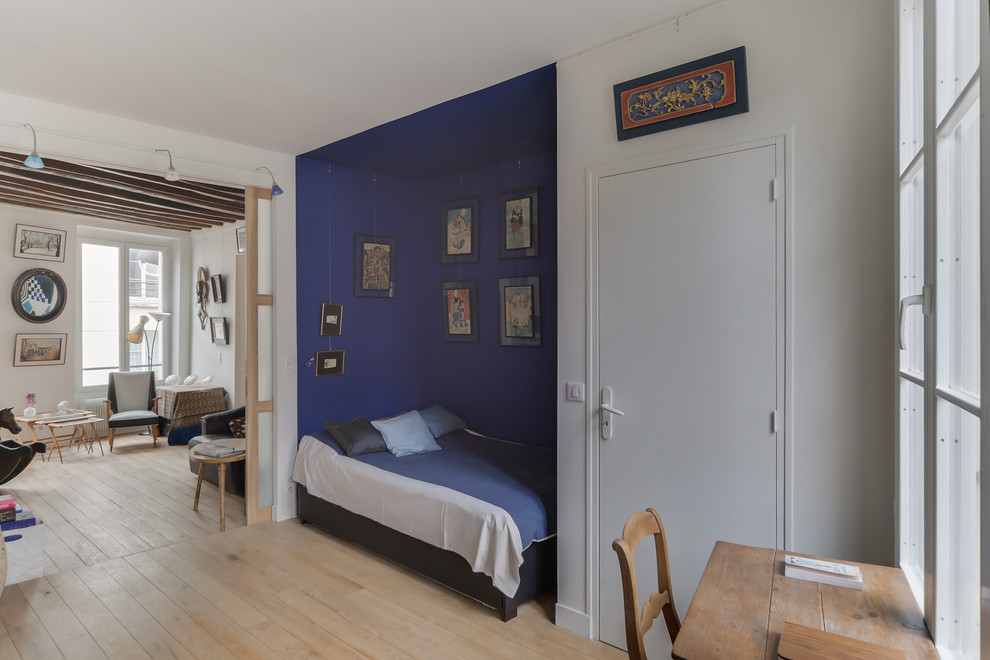 Aménagement d'une grande chambre d'amis contemporaine avec un mur bleu, parquet clair, aucune cheminée et un sol beige.