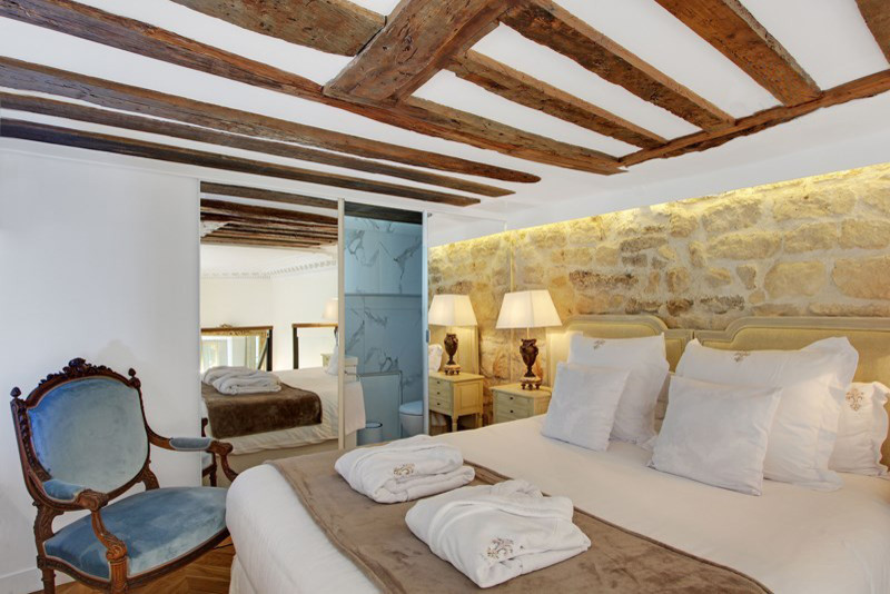 Imagen de dormitorio tipo loft tradicional renovado de tamaño medio sin chimenea con paredes beige, suelo de madera clara y suelo beige