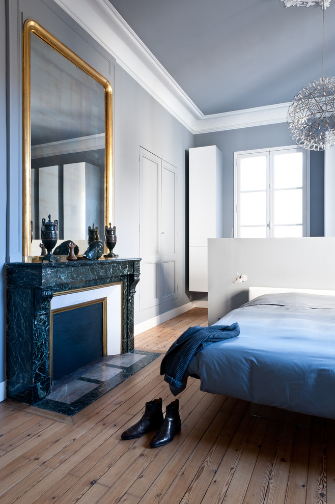 На фото: хозяйская спальня среднего размера в современном стиле с серыми стенами, светлым паркетным полом, стандартным камином, фасадом камина из камня и коричневым полом с