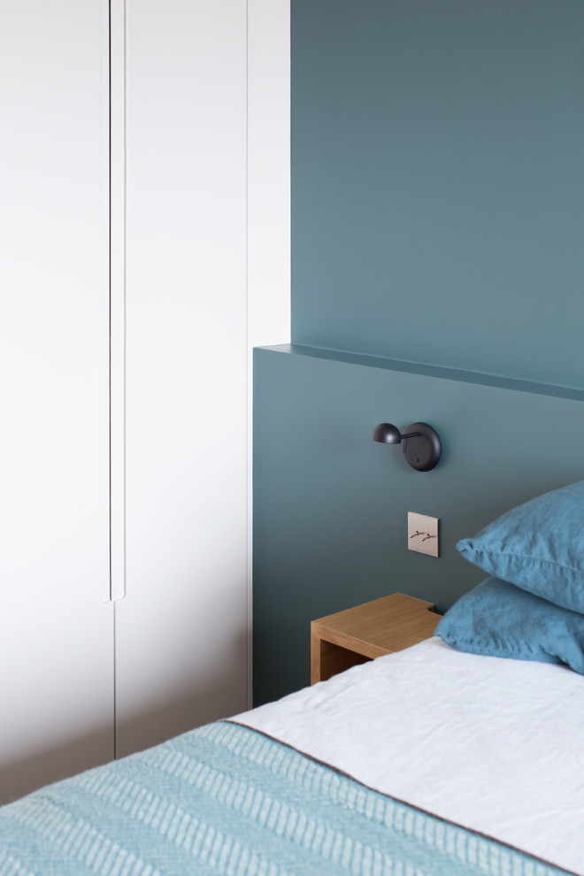 パリにある小さな北欧スタイルのおしゃれな主寝室 (青い壁、無垢フローリング)