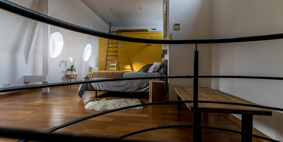 Modelo de dormitorio principal contemporáneo extra grande con paredes amarillas y suelo de madera clara