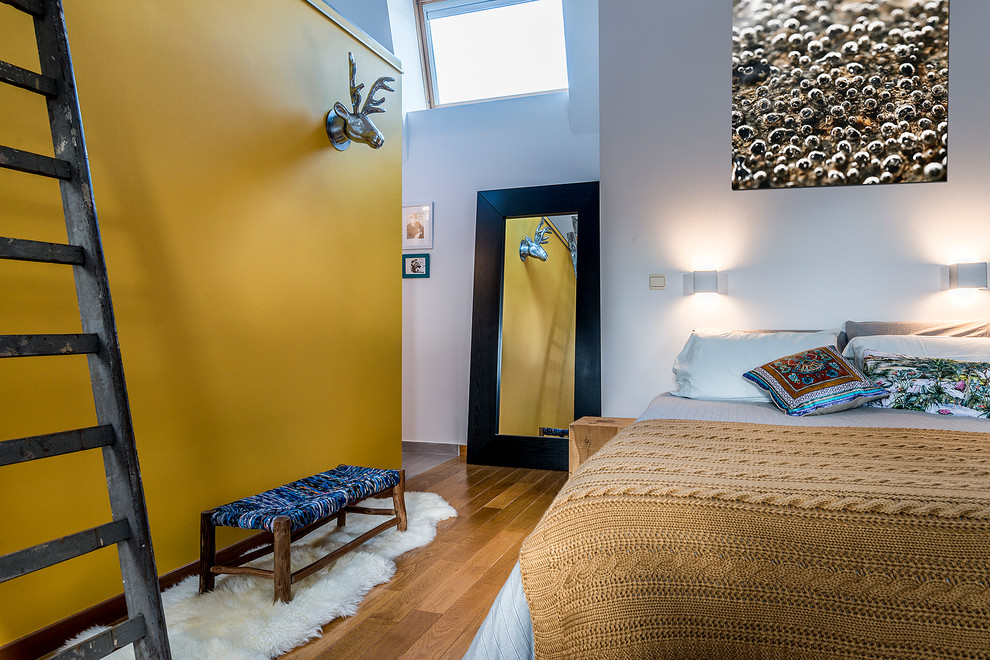 Ejemplo de dormitorio principal actual grande con paredes amarillas y suelo de madera clara