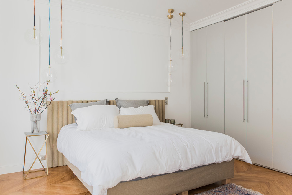 This is an example of a traditional bedroom in Paris with white walls, medium hardwood flooring and brown floors.