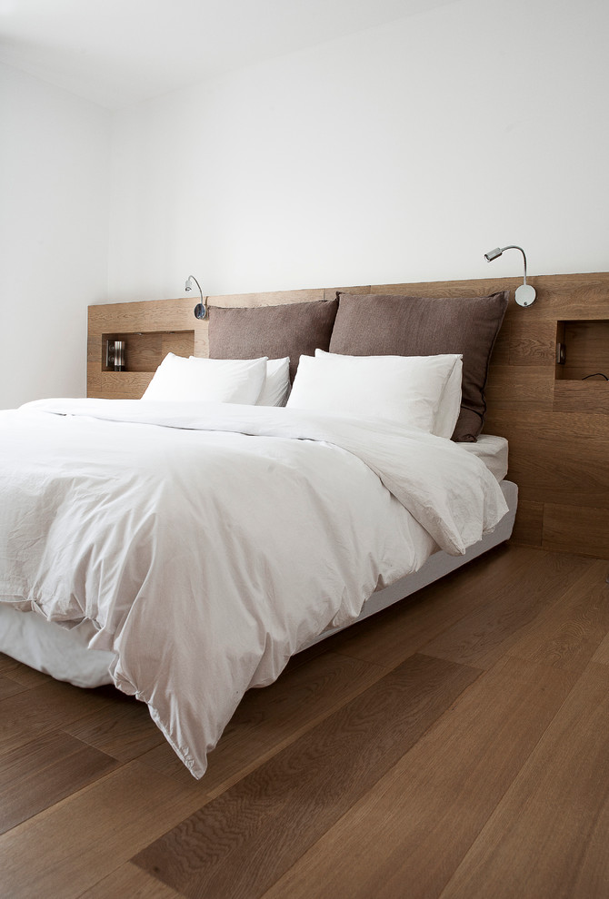 Aménagement d'une chambre parentale moderne de taille moyenne avec un mur blanc et un sol en bois brun.