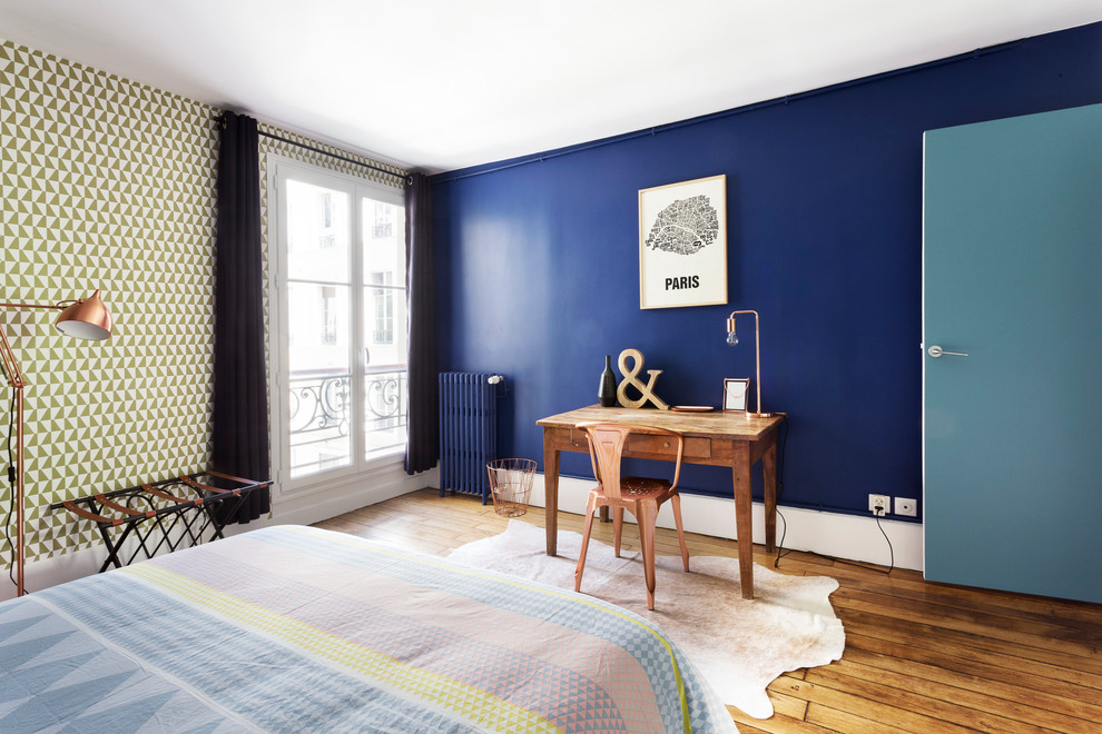 Réalisation d'une grande chambre design avec un mur bleu et parquet foncé.