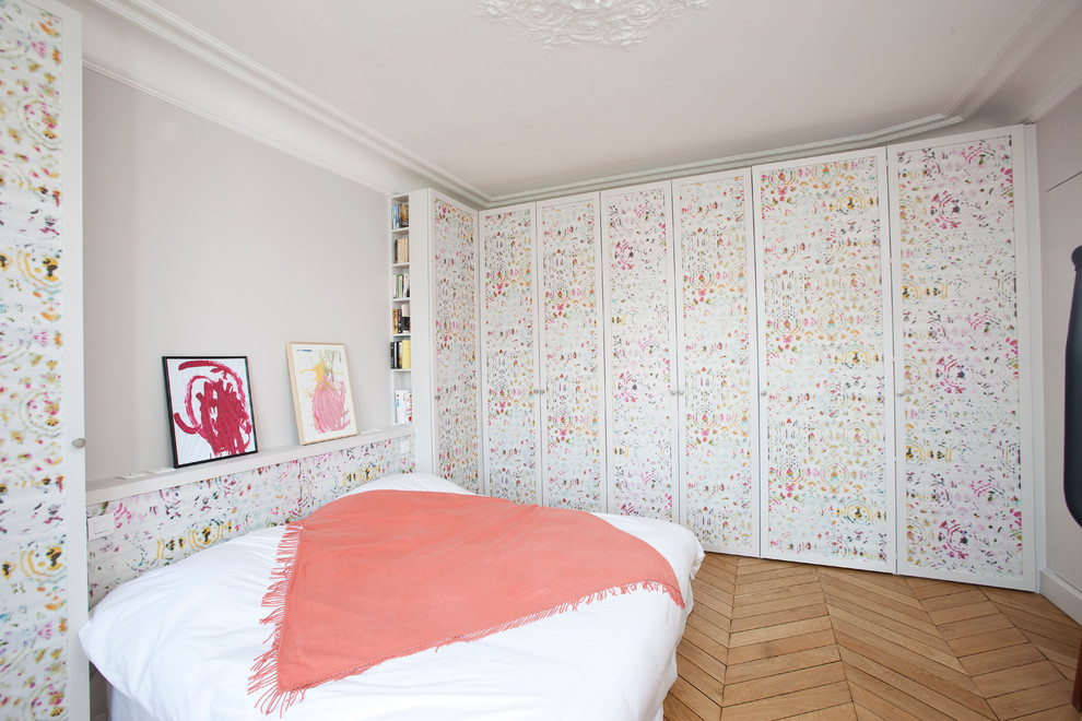 Aménagement d'une chambre parentale contemporaine de taille moyenne avec un mur multicolore et un sol en bois brun.