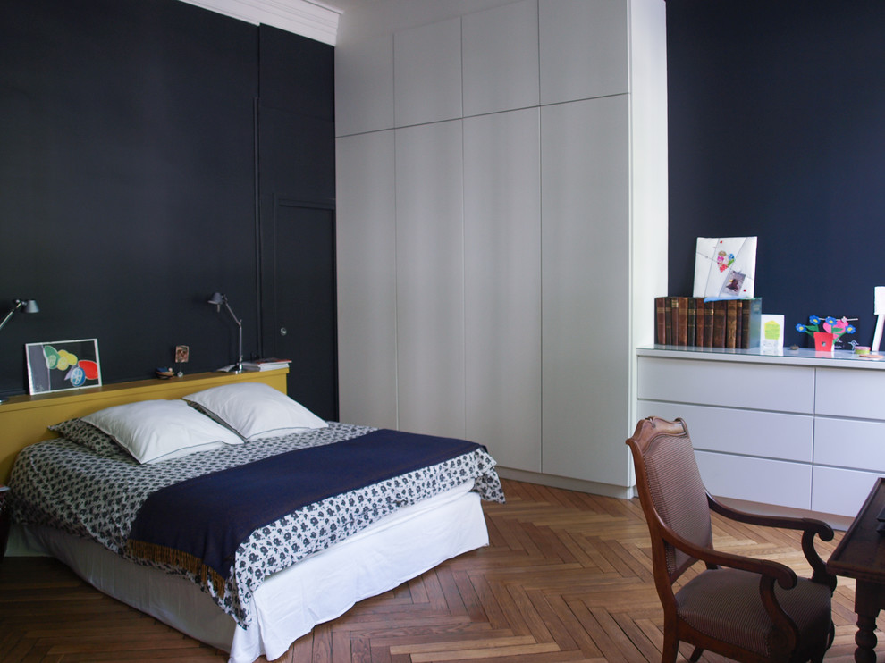 Idée de décoration pour une grande chambre parentale design avec un mur bleu et un sol en bois brun.