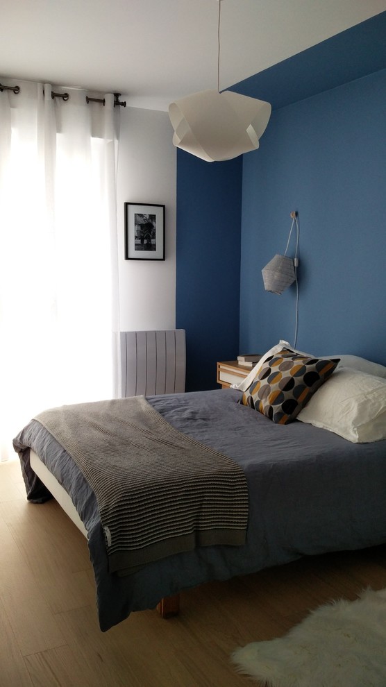 Modelo de dormitorio principal escandinavo de tamaño medio con paredes azules y suelo de madera clara