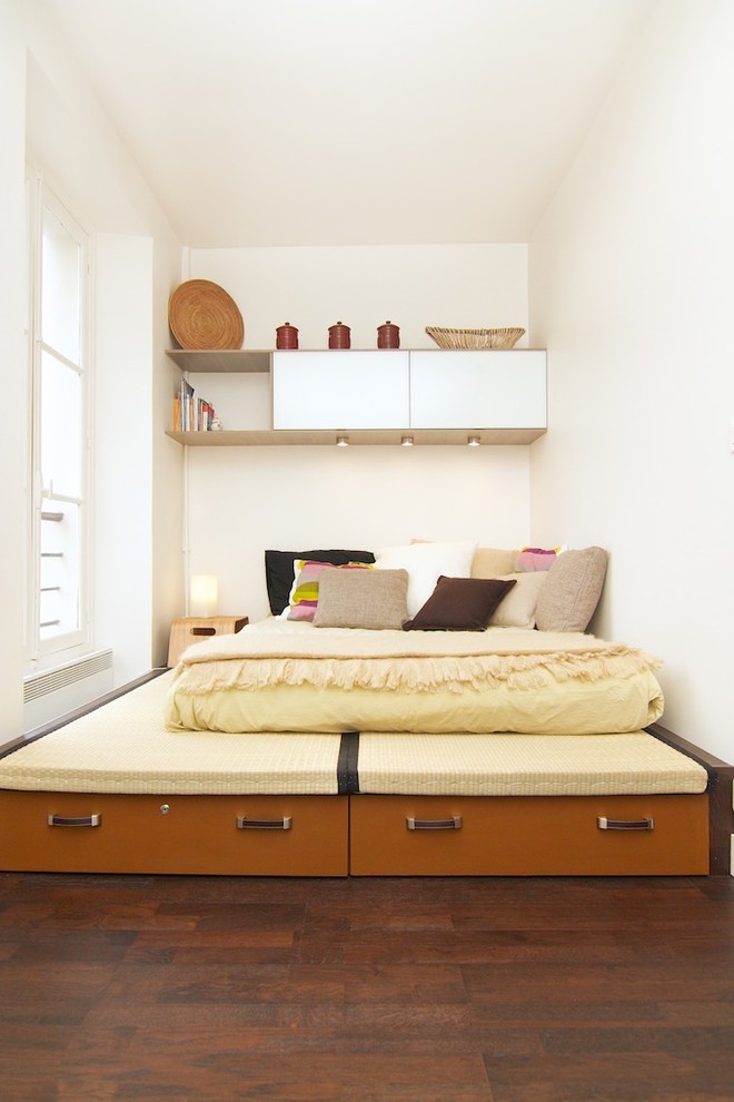 Cette image montre une petite chambre parentale design avec un mur blanc et parquet foncé.