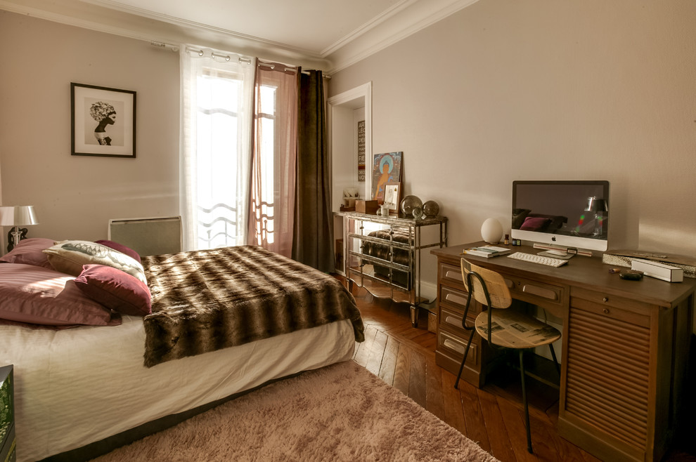 Ejemplo de dormitorio principal bohemio grande sin chimenea con paredes grises, suelo de madera en tonos medios, suelo marrón y con escritorio
