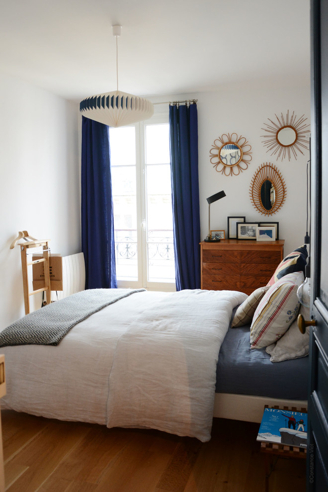 Inspiration for an eclectic bedroom in Paris with white walls and medium hardwood flooring.