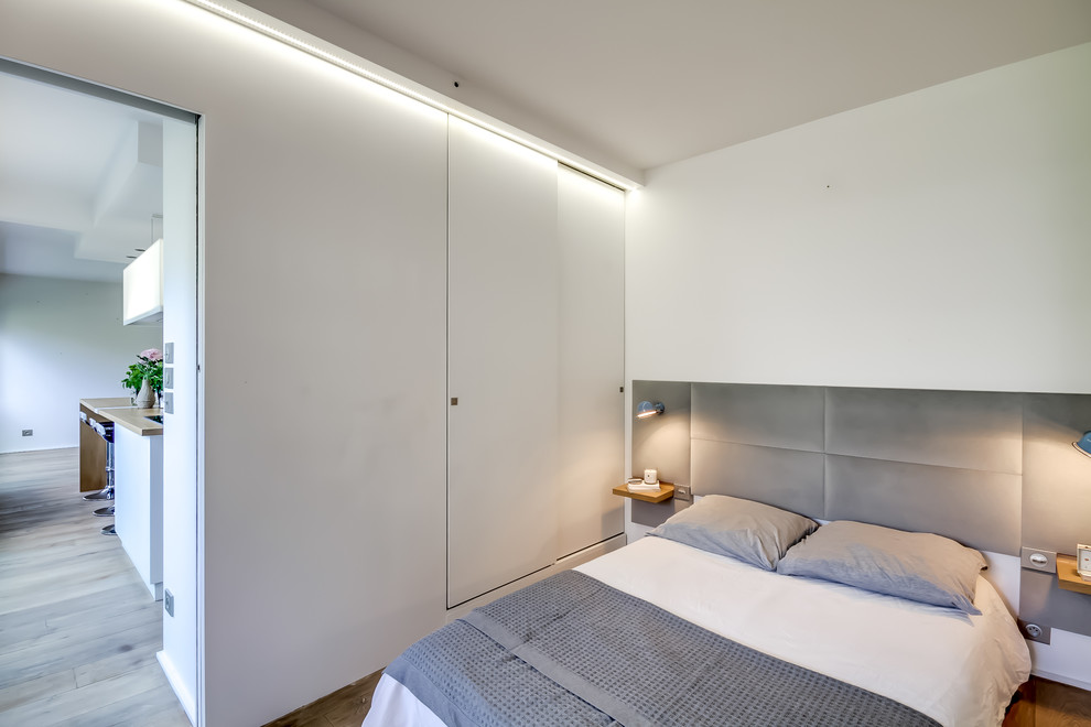 Foto de dormitorio principal y gris y blanco escandinavo de tamaño medio sin chimenea con paredes blancas, suelo de madera en tonos medios y suelo marrón