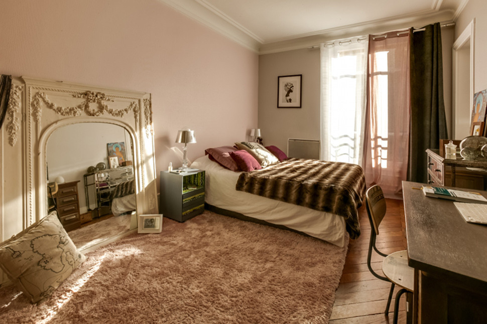 Photo of a large eclectic master bedroom in Paris with pink walls, medium hardwood flooring, no fireplace and brown floors.