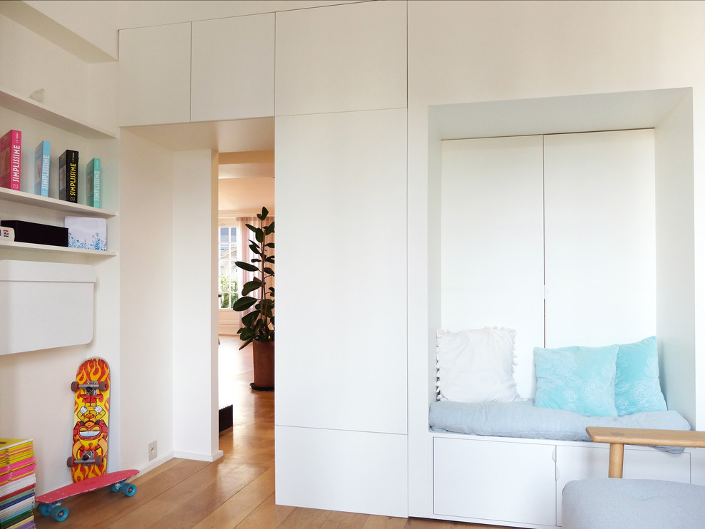 Cette image montre une chambre d'amis design de taille moyenne avec un mur blanc, parquet clair, une cheminée d'angle, un manteau de cheminée en pierre et un sol beige.