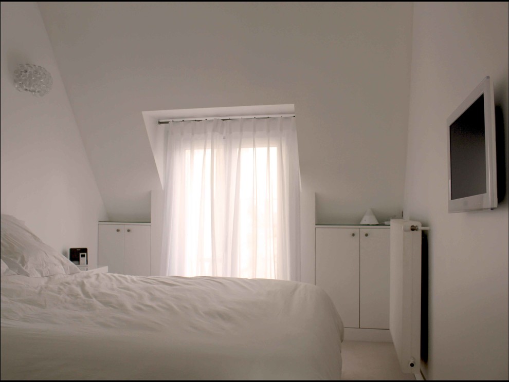 Modelo de dormitorio tipo loft moderno de tamaño medio con paredes blancas y moqueta