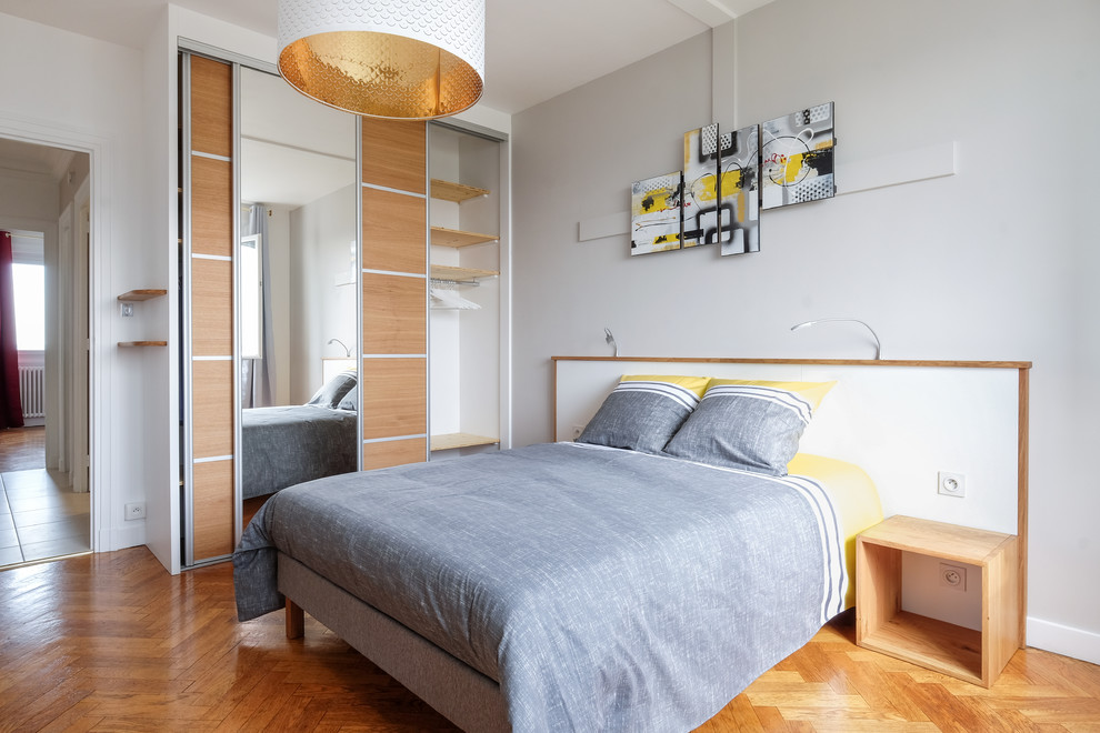 Contemporary bedroom in Lyon with white walls and medium hardwood flooring.