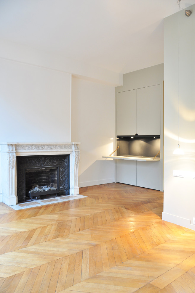 Cette photo montre une grande chambre parentale tendance avec un mur blanc, parquet clair, une cheminée standard et un manteau de cheminée en pierre.