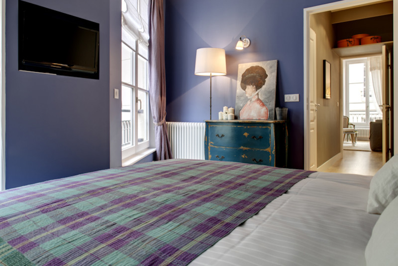Foto de dormitorio principal ecléctico pequeño sin chimenea con paredes azules, suelo de madera clara y suelo marrón