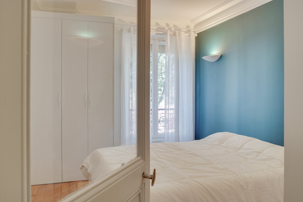 Aménagement d'une chambre parentale moderne de taille moyenne avec un mur bleu, parquet clair, aucune cheminée et un sol beige.