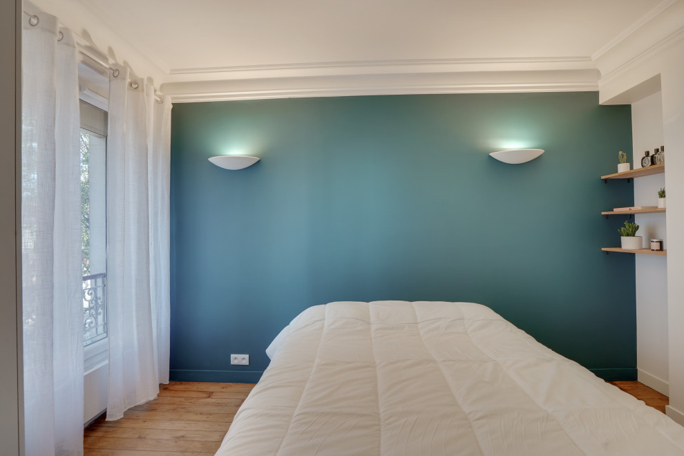 Idée de décoration pour une chambre parentale minimaliste de taille moyenne avec un mur bleu, parquet clair et aucune cheminée.