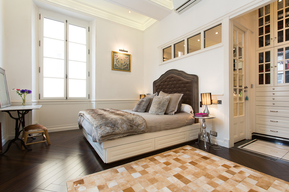 Cette photo montre une grande chambre parentale tendance avec un mur blanc et parquet foncé.