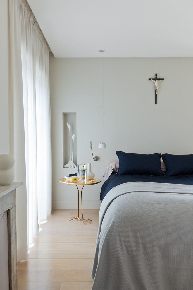 Modernes Schlafzimmer mit grauer Wandfarbe, hellem Holzboden und Kamin in Nizza